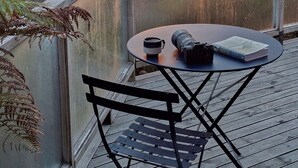 A balcony with a table and chairs, overlooking a sunset over the sea with boats. - Greenvale Bed and Breakfast (Oban)