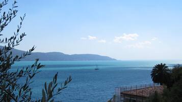 Vista sulla costa con cielo sereno, mare calmo e montagne in lontananza.