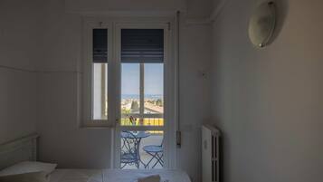 Un dormitorio con cama, ventana con vista a la ciudad y balcón con mesa y sillas.