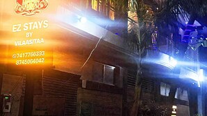 Un edificio con un letrero que dice 'EZ STAYS BY VILAASITAA' y números de contacto.