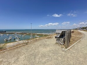 Eine Küstenlandschaft mit Sandstrand, einer Holzumzäunung und einer Reihe von Booten im Wasser.