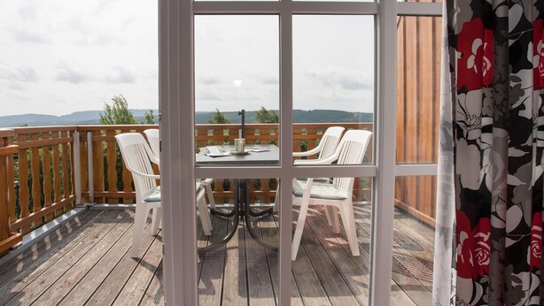 A wooden deck with a table and chairs, a view of the landscape, and a wooden fence. - Ferienwohnung mit Aussicht, Neuastenberg (Winterberg)