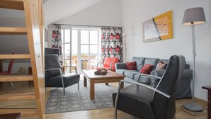 A living room with a sofa, chairs, a coffee table, a floor lamp, and a large window with curtains. - Ferienwohnung mit Aussicht, Neuastenberg (Winterberg)