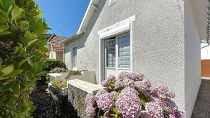 A house with a white exterior, a window with patterned glass, and a garden with pink hydrangea flowers. - Brin de Muguet by Interhome (Tharon Plage)
