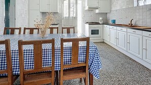 A kitchen with white cabinets, a dining table with blue checkered tablecloths, and a stove. - Brin de Muguet by Interhome (Tharon Plage)