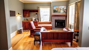 A cozy living room with a fireplace, wooden furniture, and a view of the kitchen. - Spacious Mountain Retreat | Perfect for Relaxation & Scenic Views (East Stroudsburg)