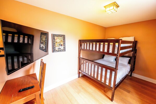Habitación con literas, un escritorio de madera y una televisión.