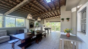 A spacious living area with a high ceiling, a fireplace, a dining table, and a sofa.