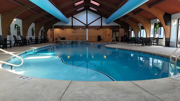 En stor indendørs swimmingpool med hvælvet loft og træbjælker.