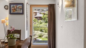 A dining area with a table, chairs, a potted plant, and a view of a garden through a glass door. - Zermatt, 4 pers/3 lits - Balcon avec vue & jardin (Zermatt)