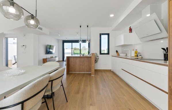 A modern kitchen with a central island, wooden flooring, and white cabinetry. - Pet friendly home in San Javier (San Javier)