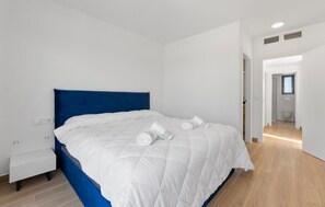 Una habitación de hotel moderna con una cama grande, una mesita de noche y vistas al baño.