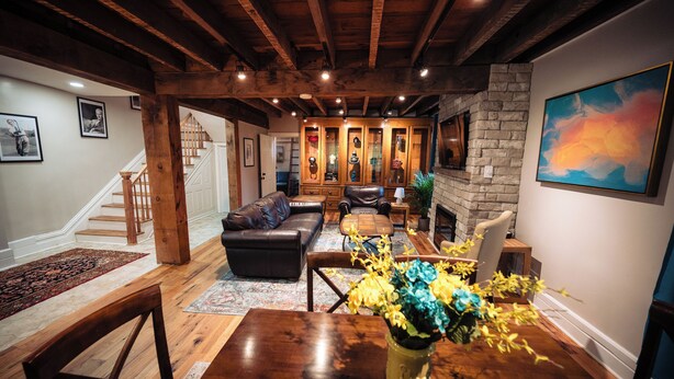A spacious living room with a fireplace, wooden beams, a staircase, and a dining area with a table and chairs.