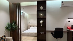 A modern bedroom with a bed, a desk, a chair, and a shelf with decorative items. - Luxury & Comfort in Prime Al-Qairawan Location!
Modern Design, 5G Internet (Riyadh)