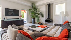 A modern living room with a sectional sofa, a flat-screen TV, a potted plant, and a fireplace. - Gorgeous home in Les Adrets-de-l'Estére (les Adrets-de-l'Estére)