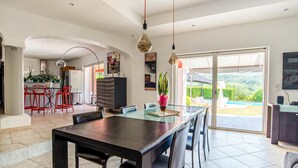 A modern dining area with a glass table and chairs, a kitchen in the background, and a view of a swimming pool. - Gorgeous home in Les Adrets-de-l'Estére (les Adrets-de-l'Estére)