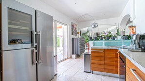 A modern kitchen with a stainless steel refrigerator, wooden cabinets, and a glass countertop. - Gorgeous home in Les Adrets-de-l'Estére (les Adrets-de-l'Estére)