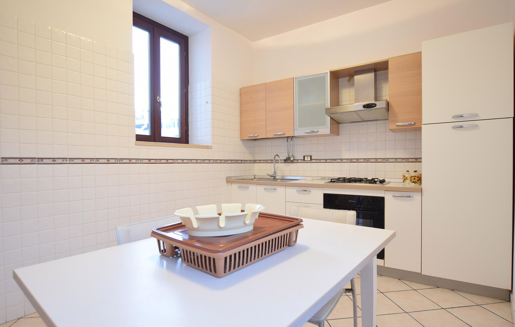 Cocina moderna con armarios blancos, una ventana y una encimera blanca con una bandeja.