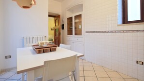 Eine Küche mit weiß gefliesten Wänden, einer weißen Arbeitsplatte und einem Fenster.