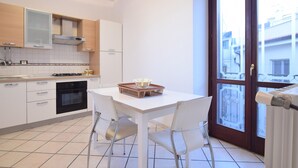Eine moderne Küche mit weißen Schränken, einem schwarzen Backofen und einem Essbereich mit weißem Tisch und zwei Stühlen.