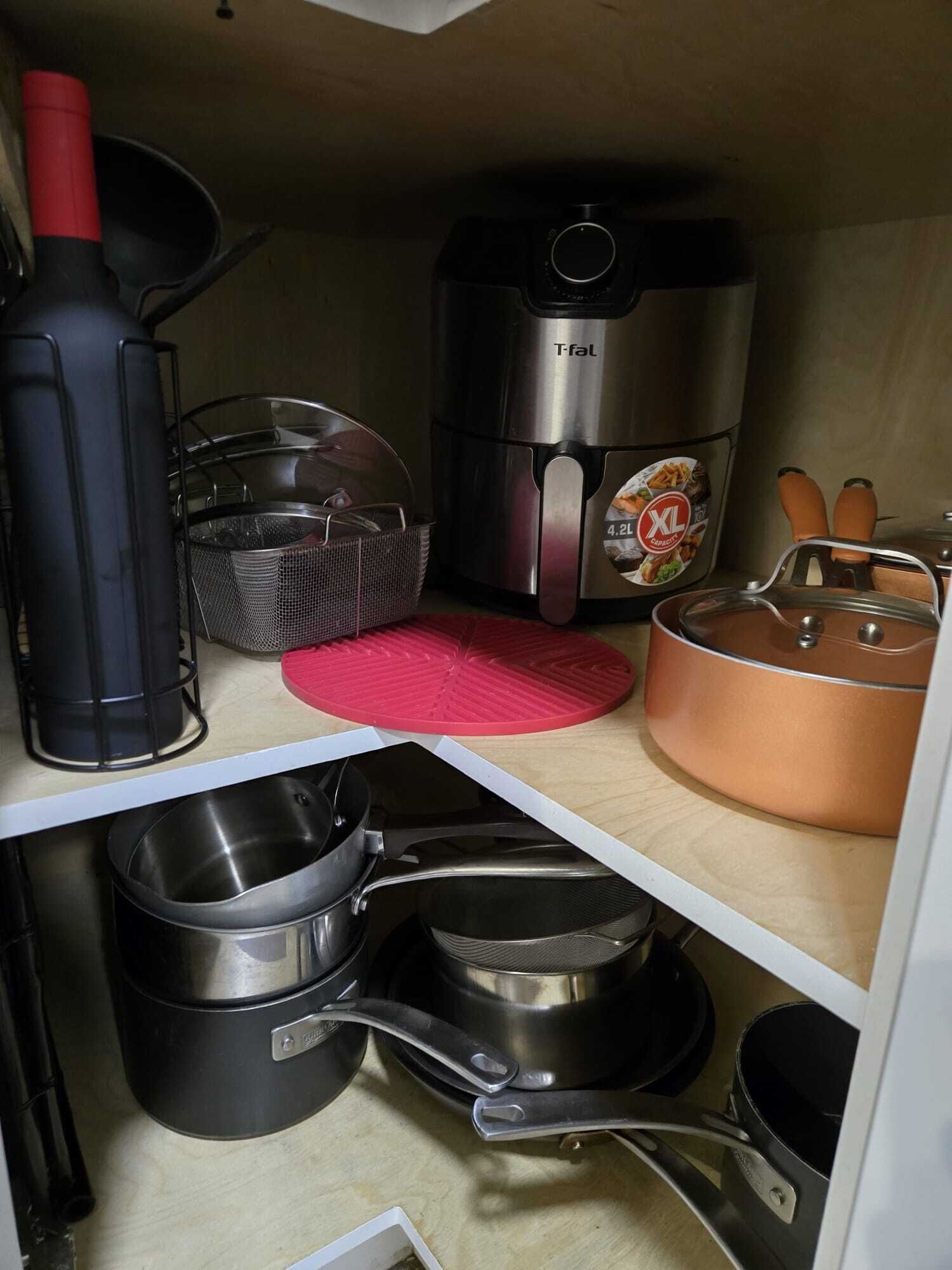 Eine Küche mit einem T-fal-Toaster, einer roten Matte, einem Kupfertopf und verschiedenen Küchenutensilien.