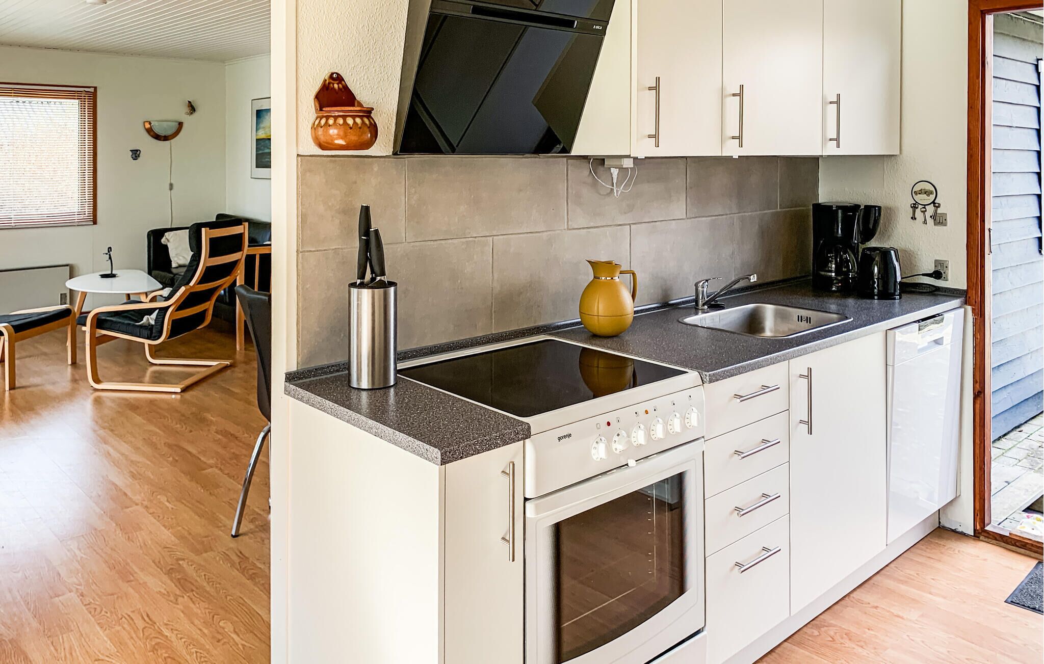 A compact kitchen with a built-in oven, a sink, and a coffee maker.