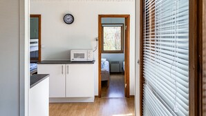 A compact kitchen with white cabinets, a microwave, and a clock on the wall.