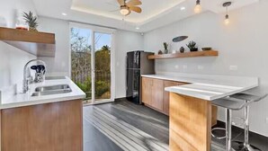 Une cuisine moderne dotée d’un îlot central, de meubles en bois et d’un réfrigérateur encastré.