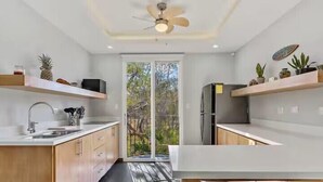 Une cuisine moderne avec des meubles en bois, un four encastré et une grande fenêtre donnant sur un jardin.