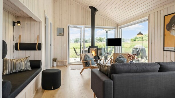 Ein gemütliches Wohnzimmer mit Kamin, bequemen Sitzmöglichkeiten und großen Fenstern mit Blick ins Freie.