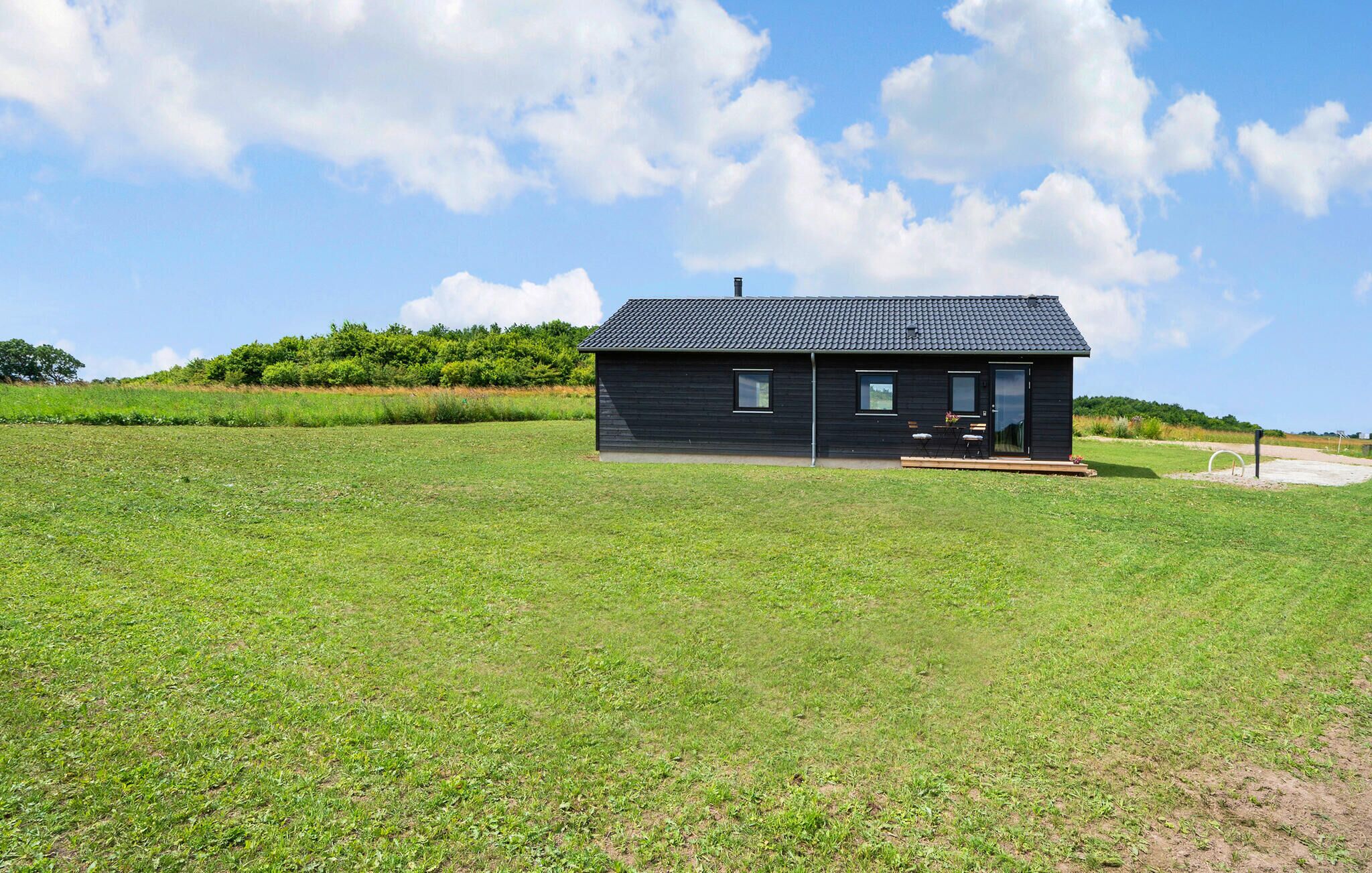 A modern black house with a flat roof, a small porch, and a clear sky.