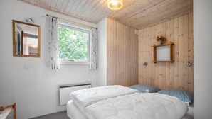 A bedroom with a bed, a window with curtains, a mirror, and a wooden wall panel. - 3 bedroom stunning home in Tarm (Tarm)