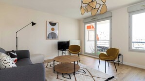 A modern living room with a sofa, two armchairs, a coffee table, a TV, and a large window with a view of buildings. - Dify Republique - Villeurbanne (Villeurbanne)