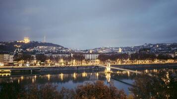A cityscape with a river, buildings, and a hill with a castle-like structure.