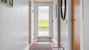 En gang med en trædør, en glasdør og et spejl på væggen.