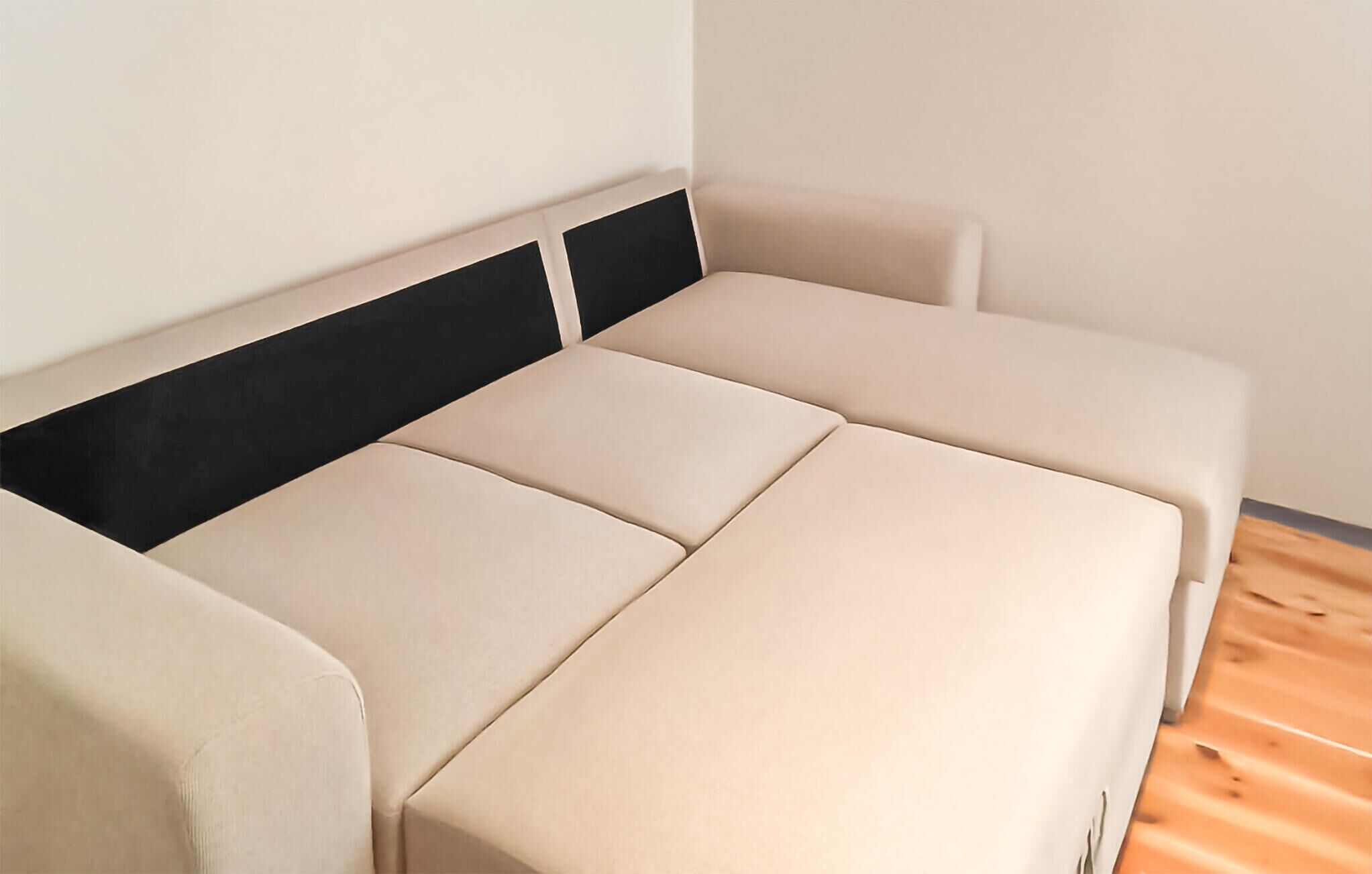 A modern, minimalist room with a sofa bed and a black headboard.