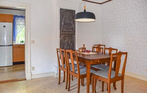 A dining area with a wooden table and chairs, a black pendant light, and a decorative wall panel. - Nice home in Gärds Köpinge (Gärds Köpinge)