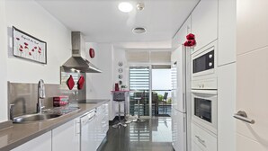 Eine moderne Küche mit weißen Schränken, Edelstahlgeräten und einem roten dekorativen Element an der Wand.