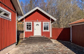A red wooden building with a white door, two windows, and a small porch. - Cozy home in Kalmar with WiFi (kalmar)