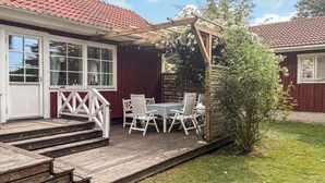 A wooden deck with outdoor furniture, a pergola, and a view of a house with a red roof. - Cozy home in Kalmar with WiFi (kalmar)