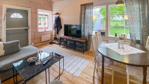 A cozy living room with a sofa, a glass coffee table, a TV, and a dining table with a placemat. - Cozy home in Kalmar with WiFi (kalmar)