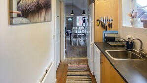 A narrow kitchen with a wooden floor, a stainless steel sink, and a dining area in the background. - Cozy home in Kalmar with WiFi (kalmar)