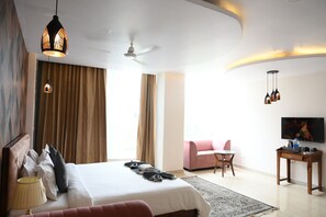 Ein modernes Hotelzimmer mit einem großen Bett, einem Schreibtisch, einem Fernseher und einem Deckenventilator.