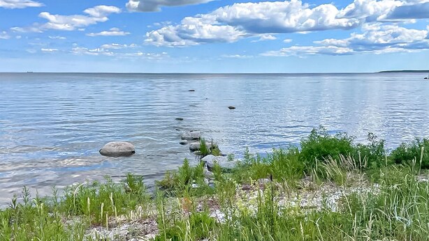 A calm lake with clear water, surrounded by grassy areas and rocks. - Stunning home in Slite with WiFi (Slite)