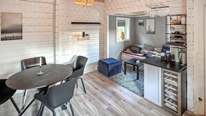Un espacio habitable compacto con comedor, kitchenette y zona de estar con sofá y mesa de centro.