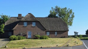A traditional brick building with a thatched roof, a small front porch, and a signboard. - Spacious Family-Friendly Apartment with Garden in Ockholm (Ockholm)