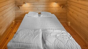 Une chambre avec un lit simple, des murs en bois et un aménagement simple et épuré.