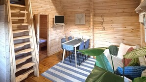 Une cabane en bois comprenant un coin repas, un lit et un téléviseur.
