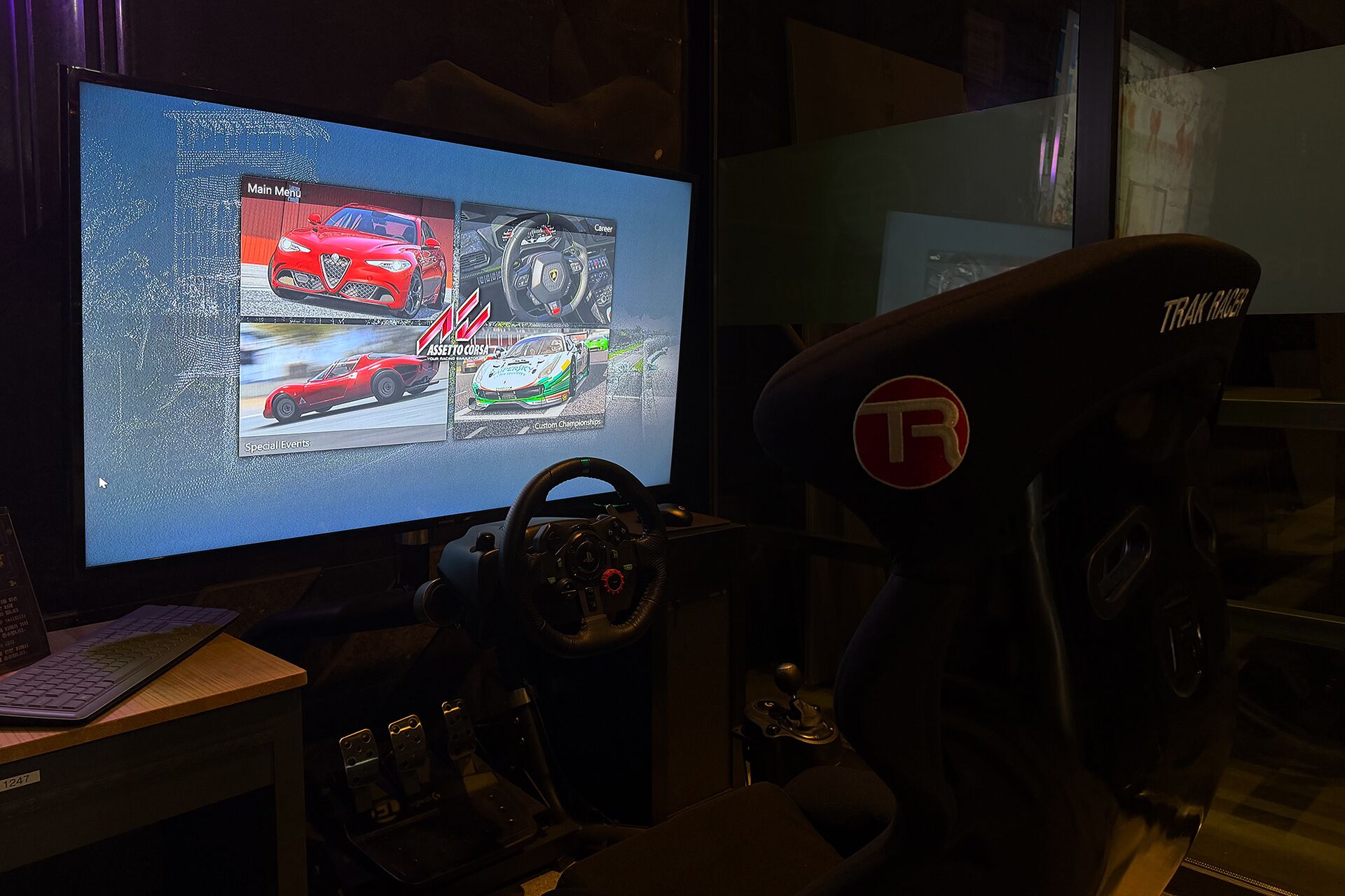 Un simulateur de course comprenant un écran affichant un jeu de course, un volant, des pédales et un siège de course de la marque TRR.