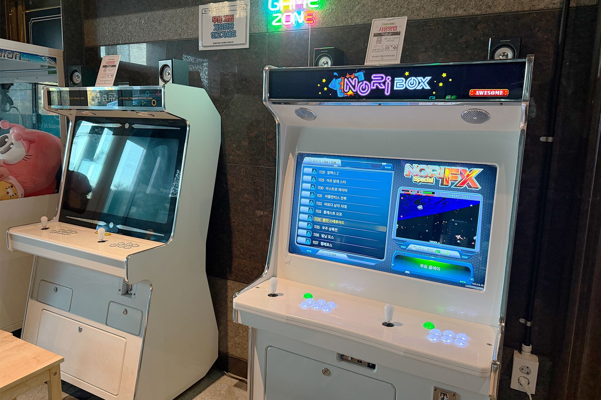 Two gaming machines with screens and control panels, one labeled "NORI BOX" and the other "GAME ZONE".